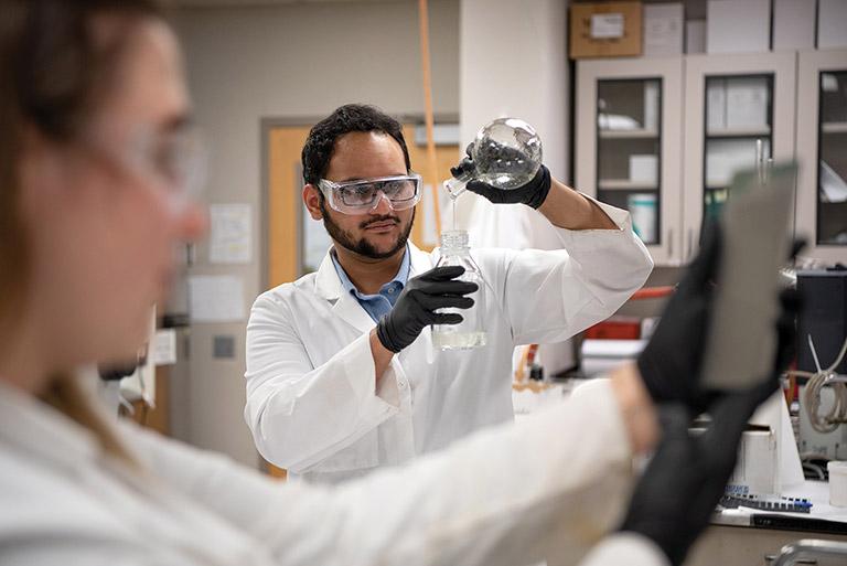 Chemistry student pouring chemical from beaker